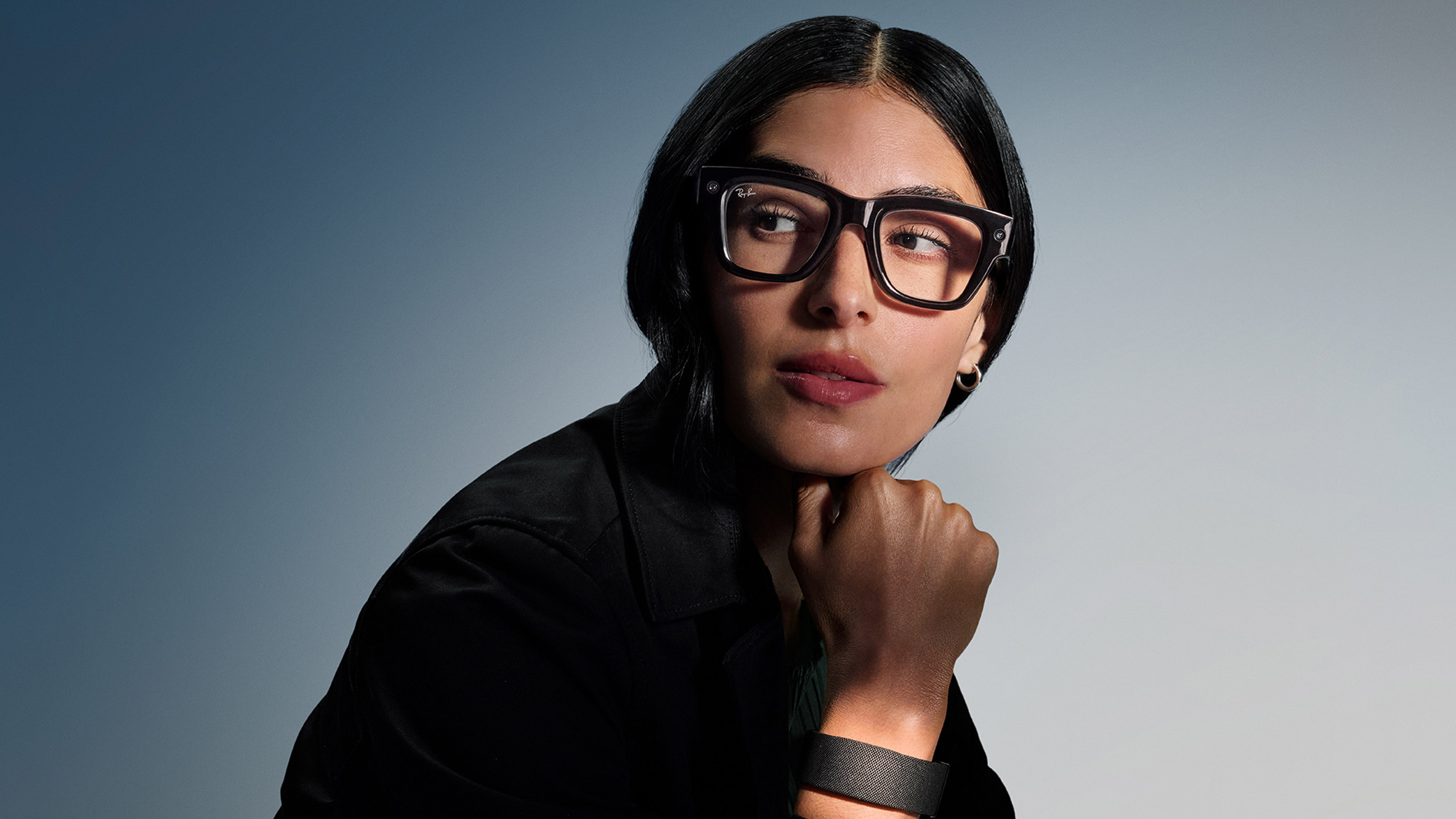 Photo of a woman wearing the Meta Ray-Ban Display glasses and Neural Band wristband