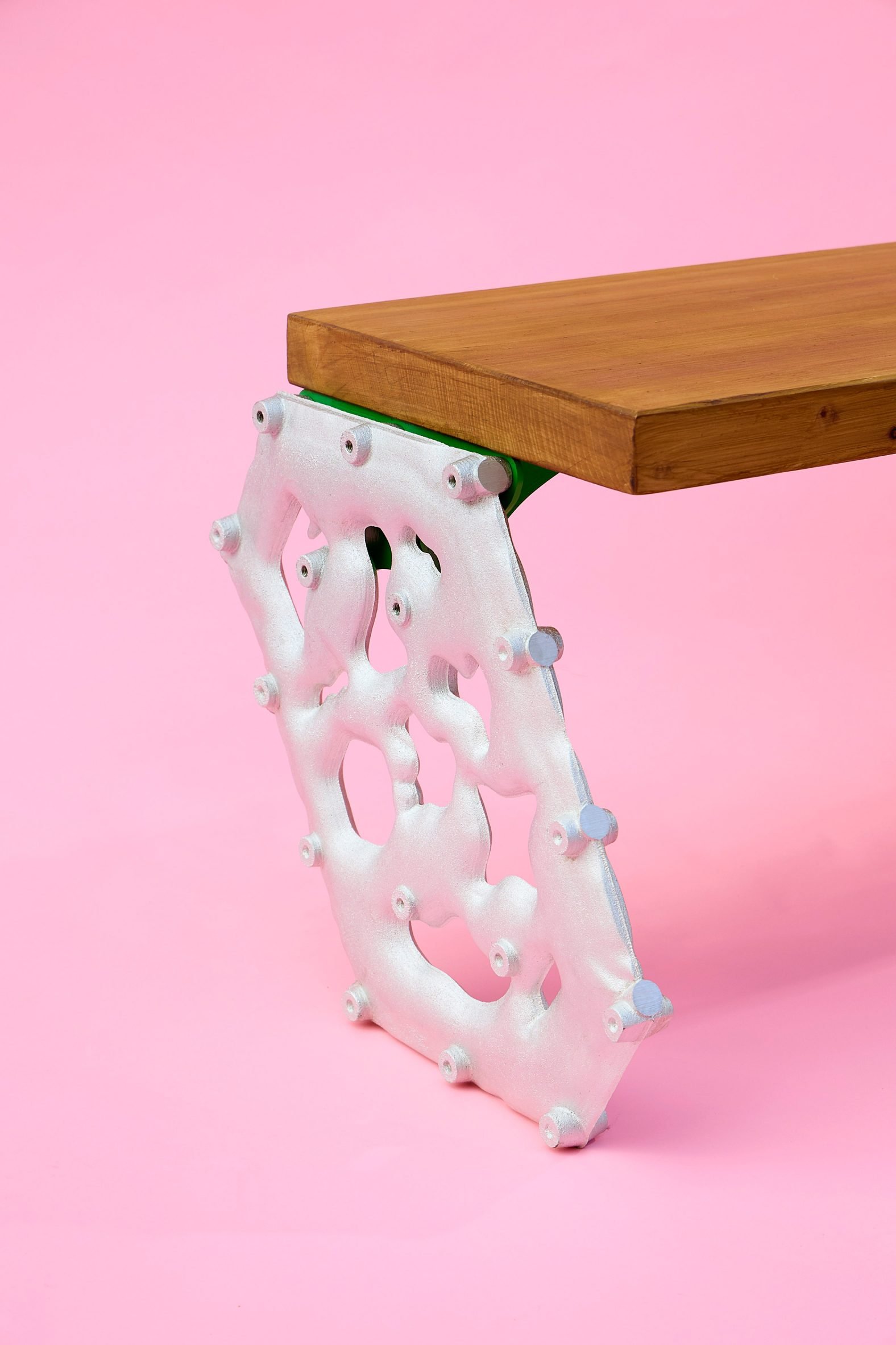 Metal legs of wooden bench on pink backdrop